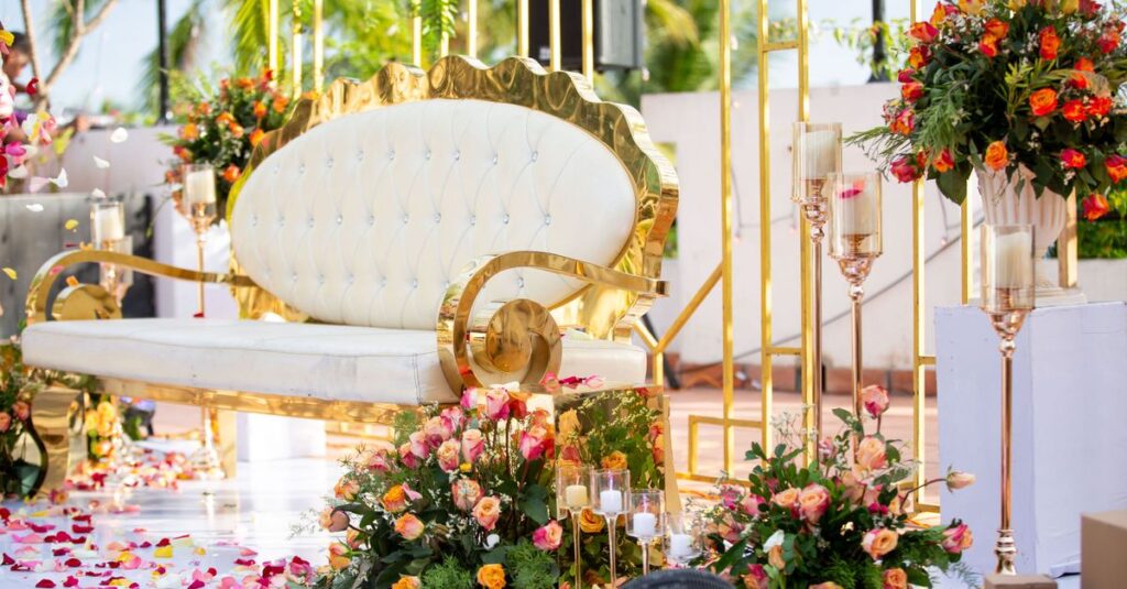 Luxurious white and gold sofa surrounded by vibrant floral arrangements, perfect for weddings.