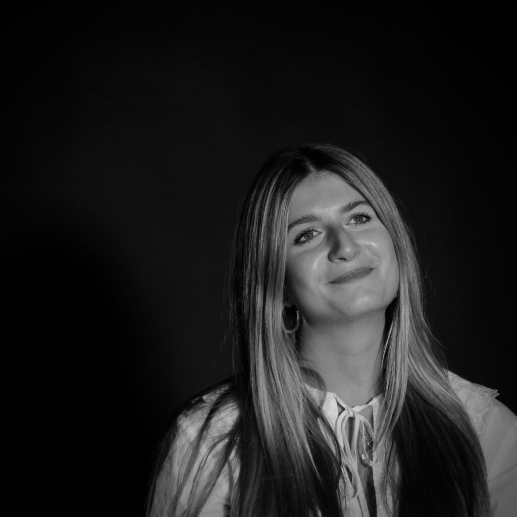 A graceful black and white portrait of a smiling young woman with long blonde hair.